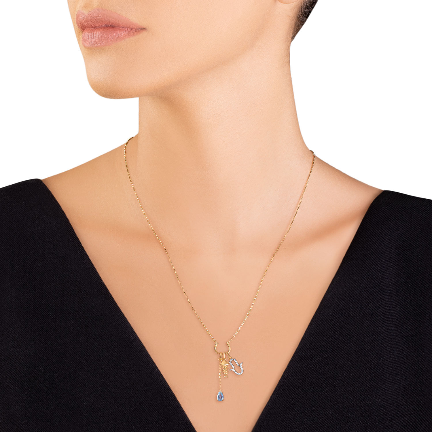 Colar dourado com pingente de letra "H" e gota azul, usado por uma mulher com pele clara e cabelo preso.
