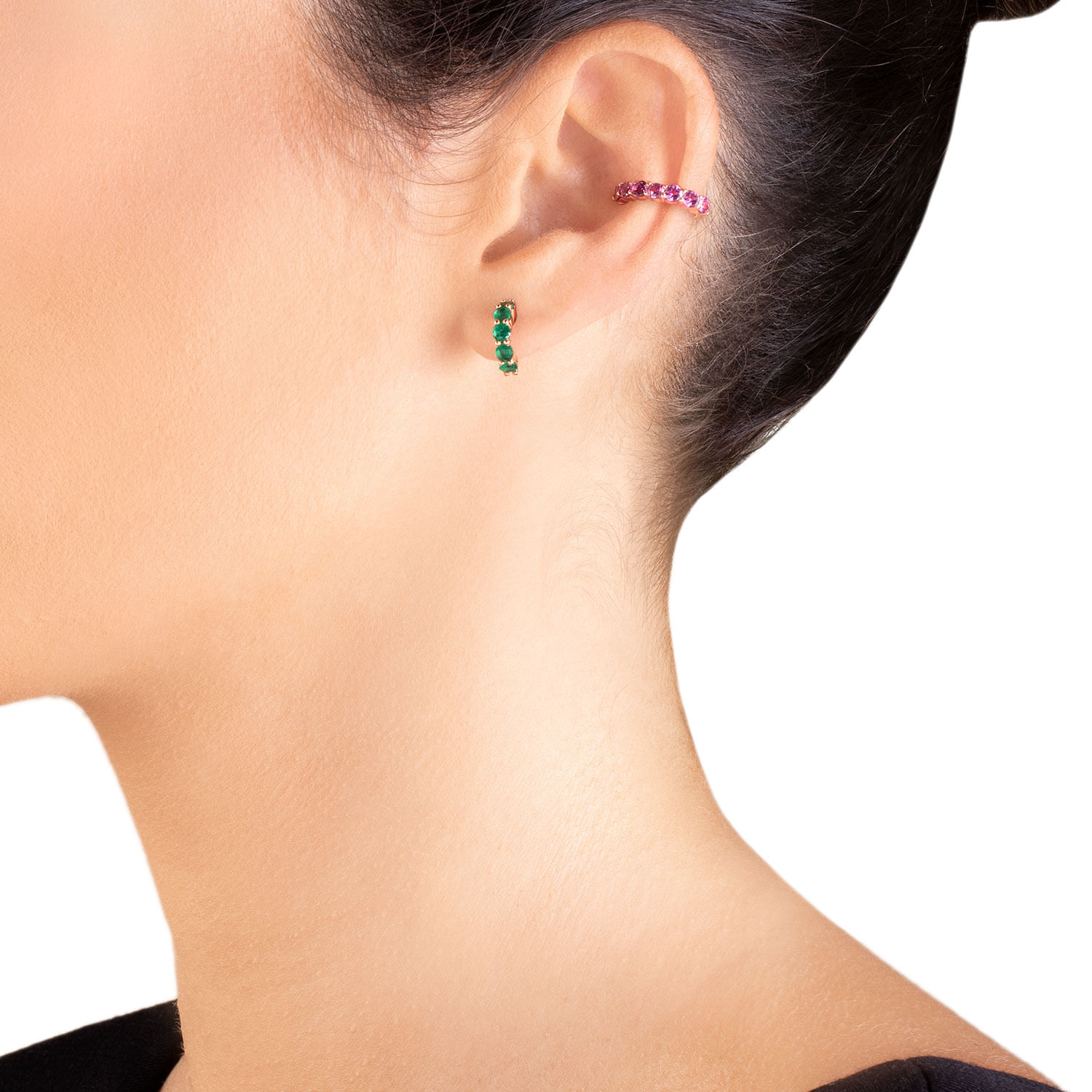 Close da orelha de uma mulher usando um ear cuff de pedra preciosa rosa e um brinco de pedra preciosa verde.
