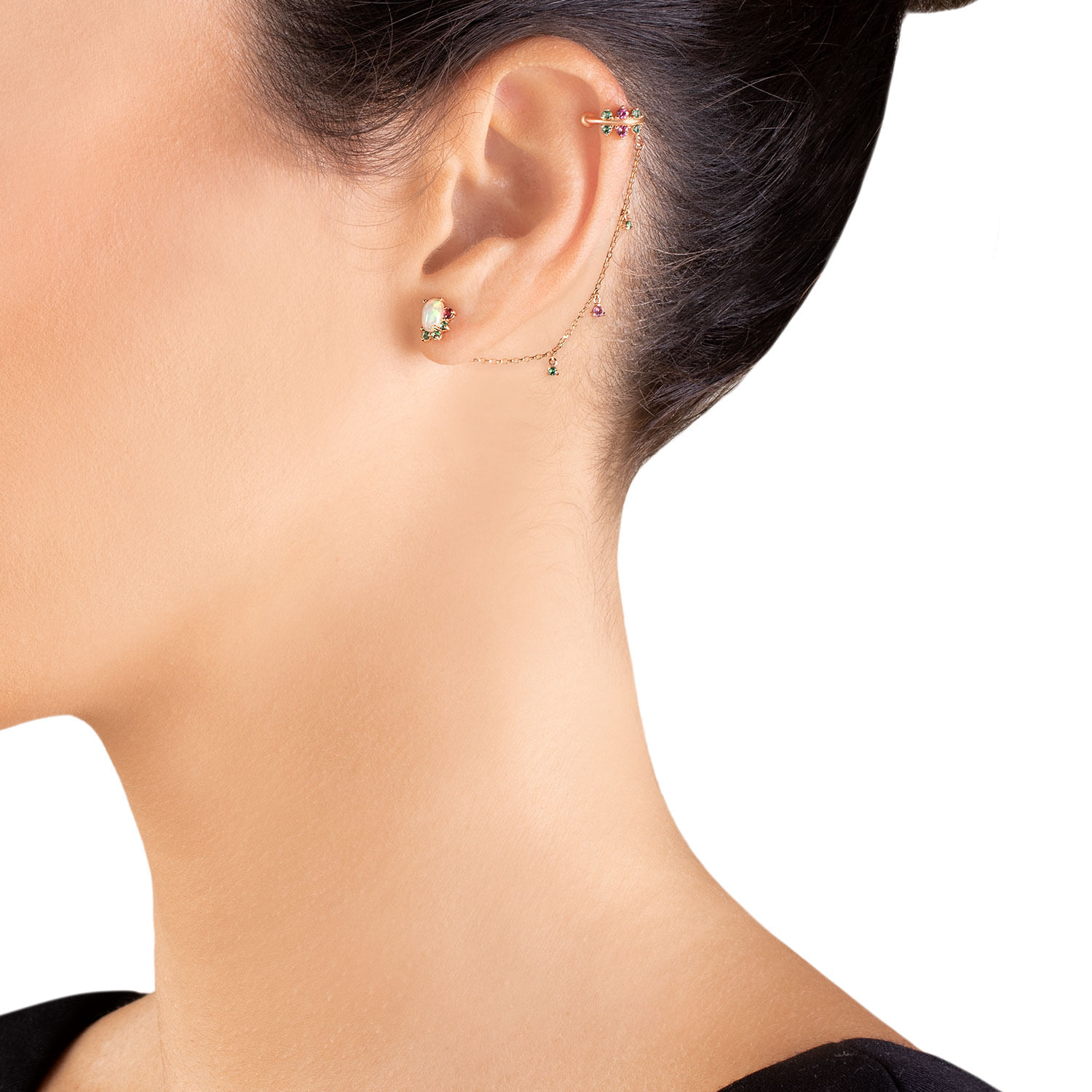 Close-up da orelha de uma mulher com vários piercings, incluindo brincos e um twister, exibindo joias delicadas.