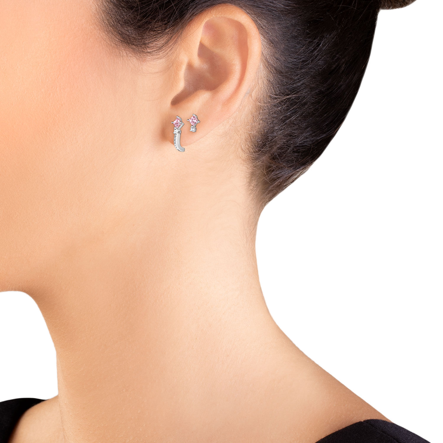 Close-up de uma orelha feminina com brincos pequenos de estrelas e uma estrela maior, usando cabelo preso e pele clara.