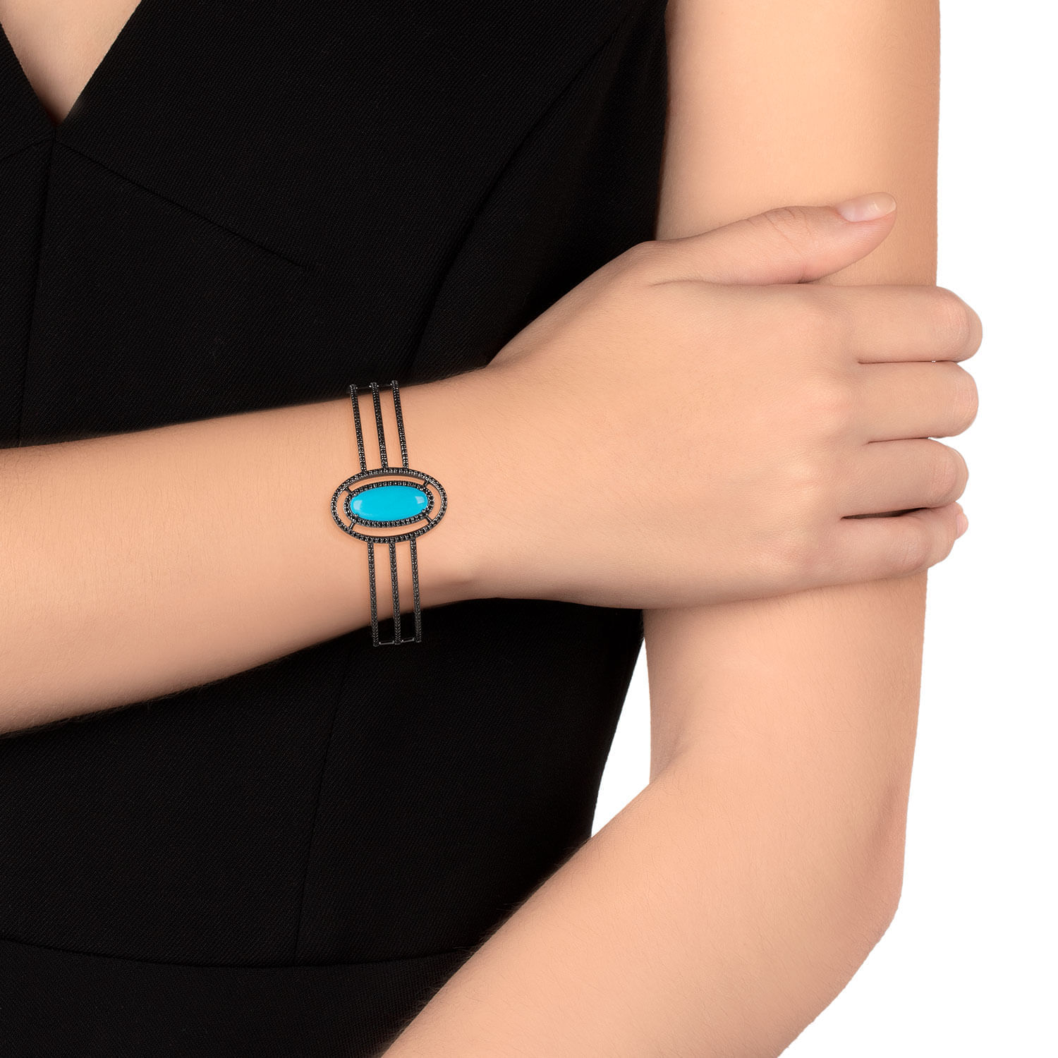 Pulseira com uma pedra azul no centro, adornada com detalhes escuros, usada no braço de uma mulher com roupa preta.