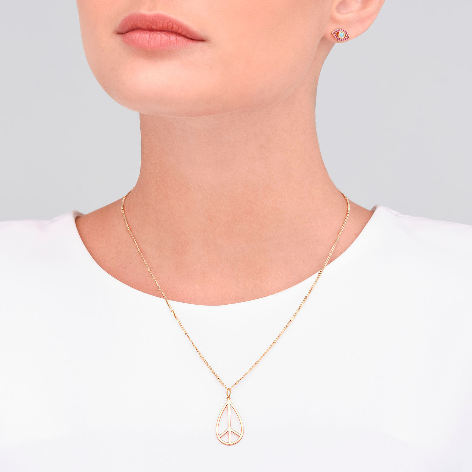 Colar dourado com pingente de paz em forma de símbolo de paz.
