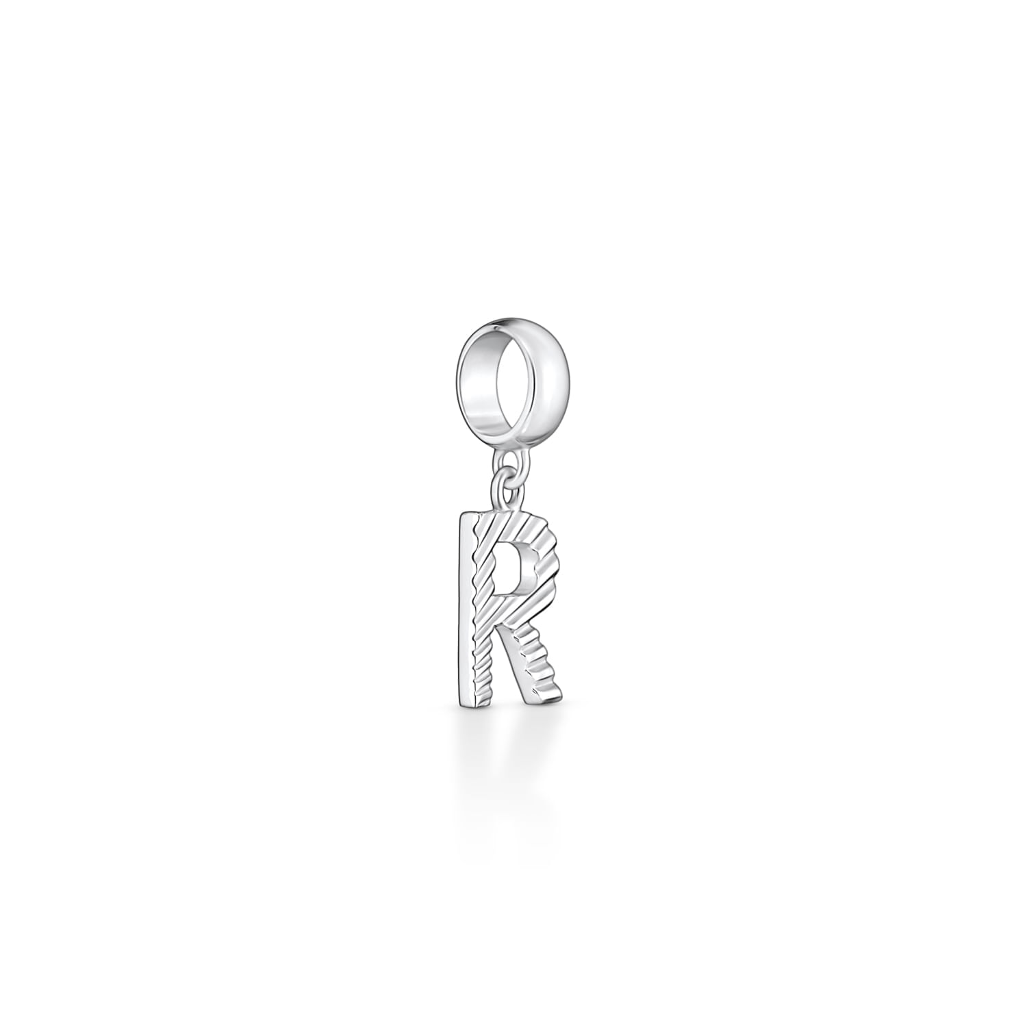 Pingente de metal prateado com forma de letra "R" com detalhes texturizados.