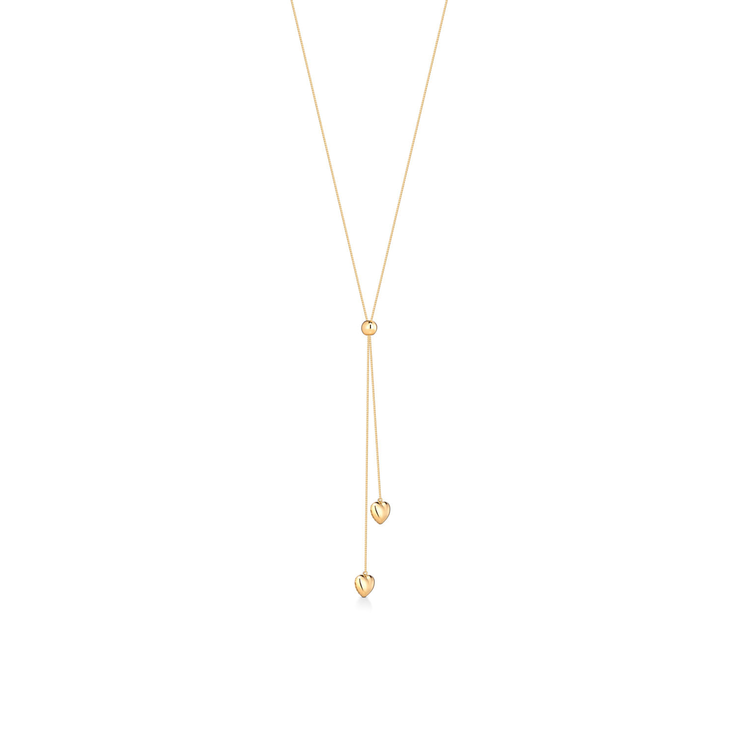 Colar dourado com corrente fina e três pingentes: uma bolinha, uma coração vazado e duas gotas.