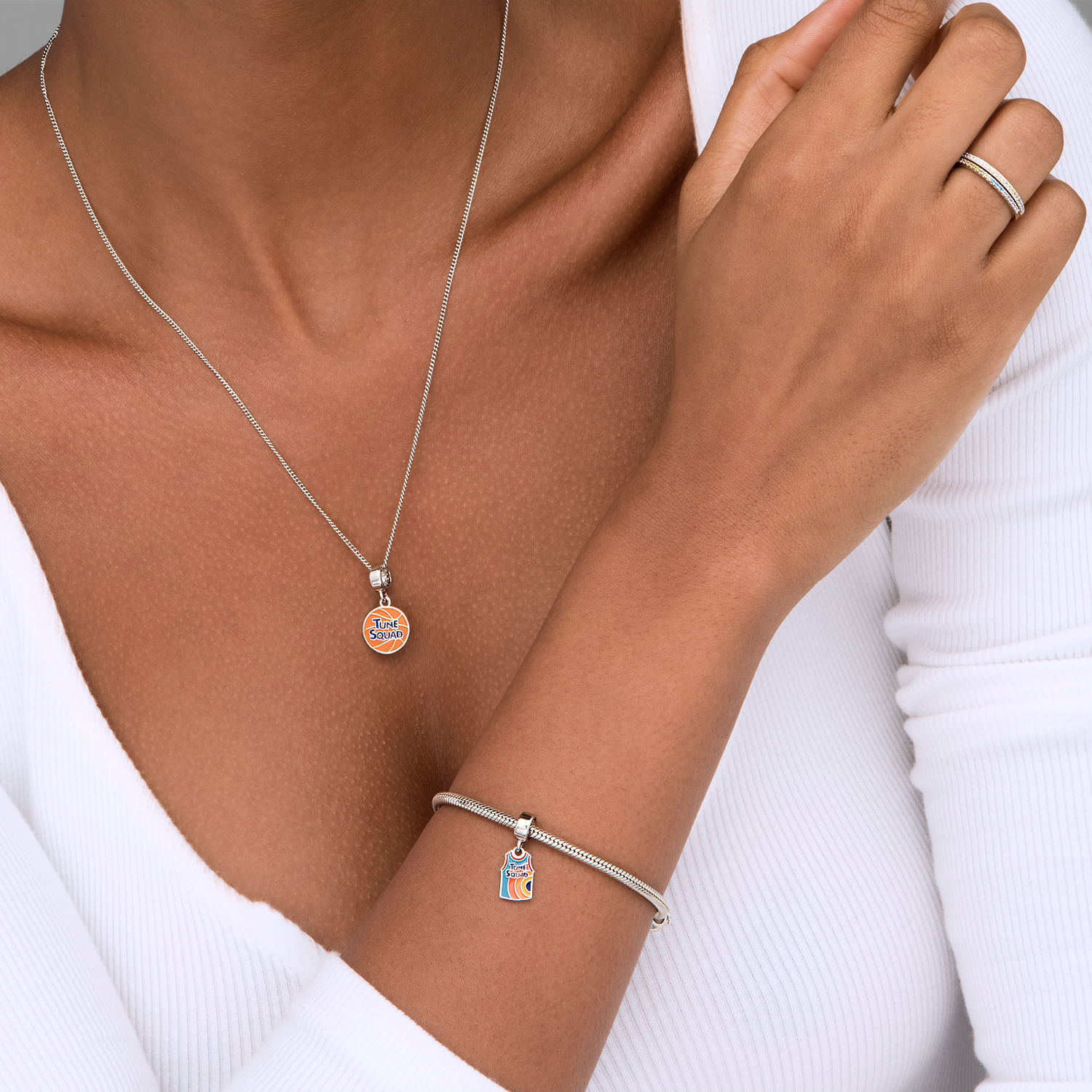 Colar e pulseira de prata com pingentes coloridos e detalhes em strass, usando uma roupa branca.