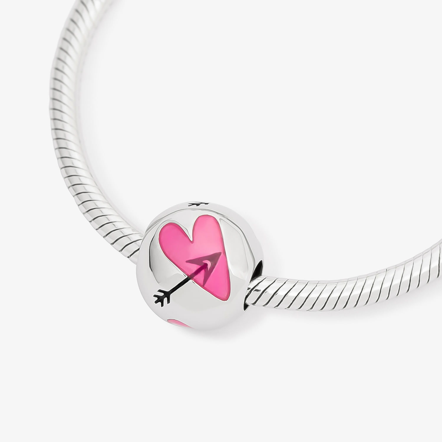 Pingente de metal prateado com coração rosa e flecha preta no centro, preso a uma corrente de metal prateado.
