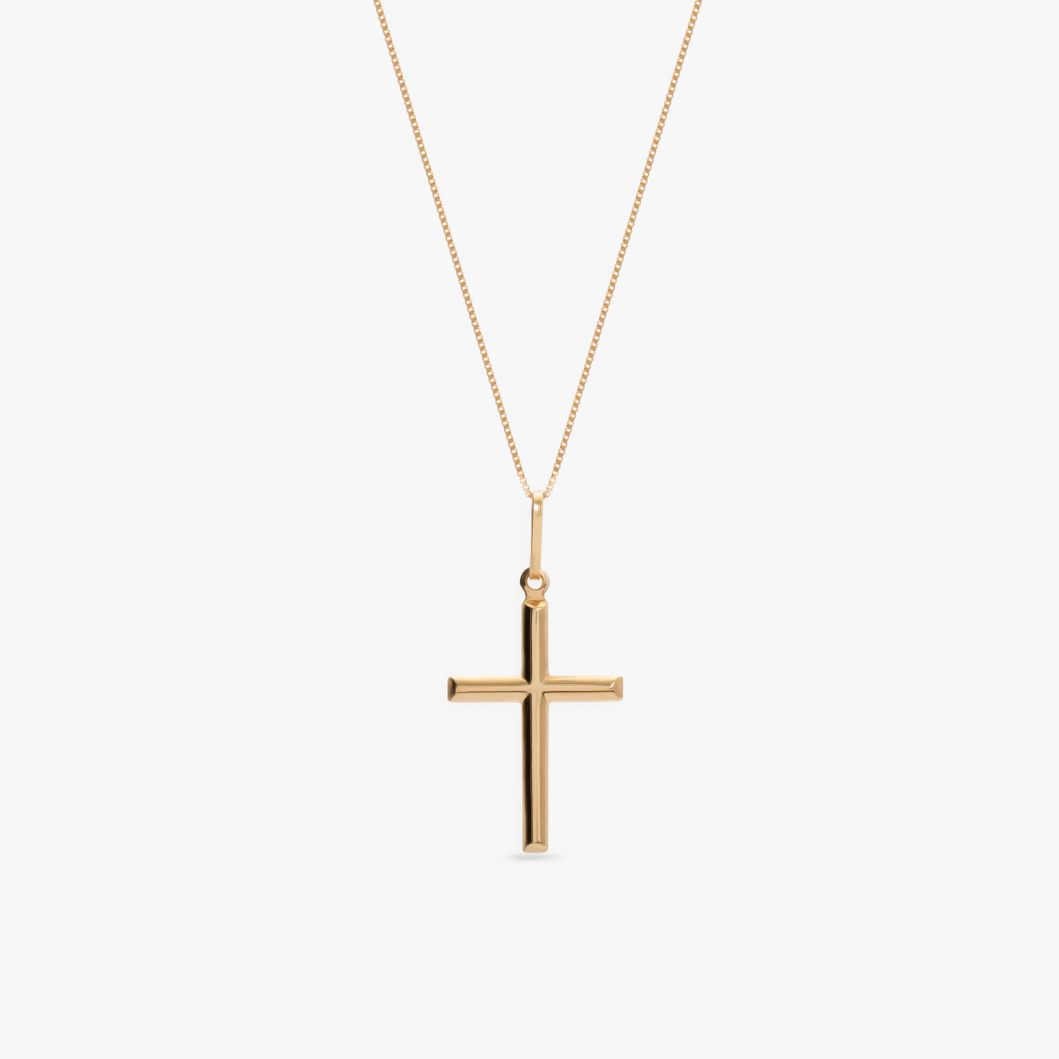 Colar com pingente de cruz dourado, em mais de um tom, com corrente fina e delicada.