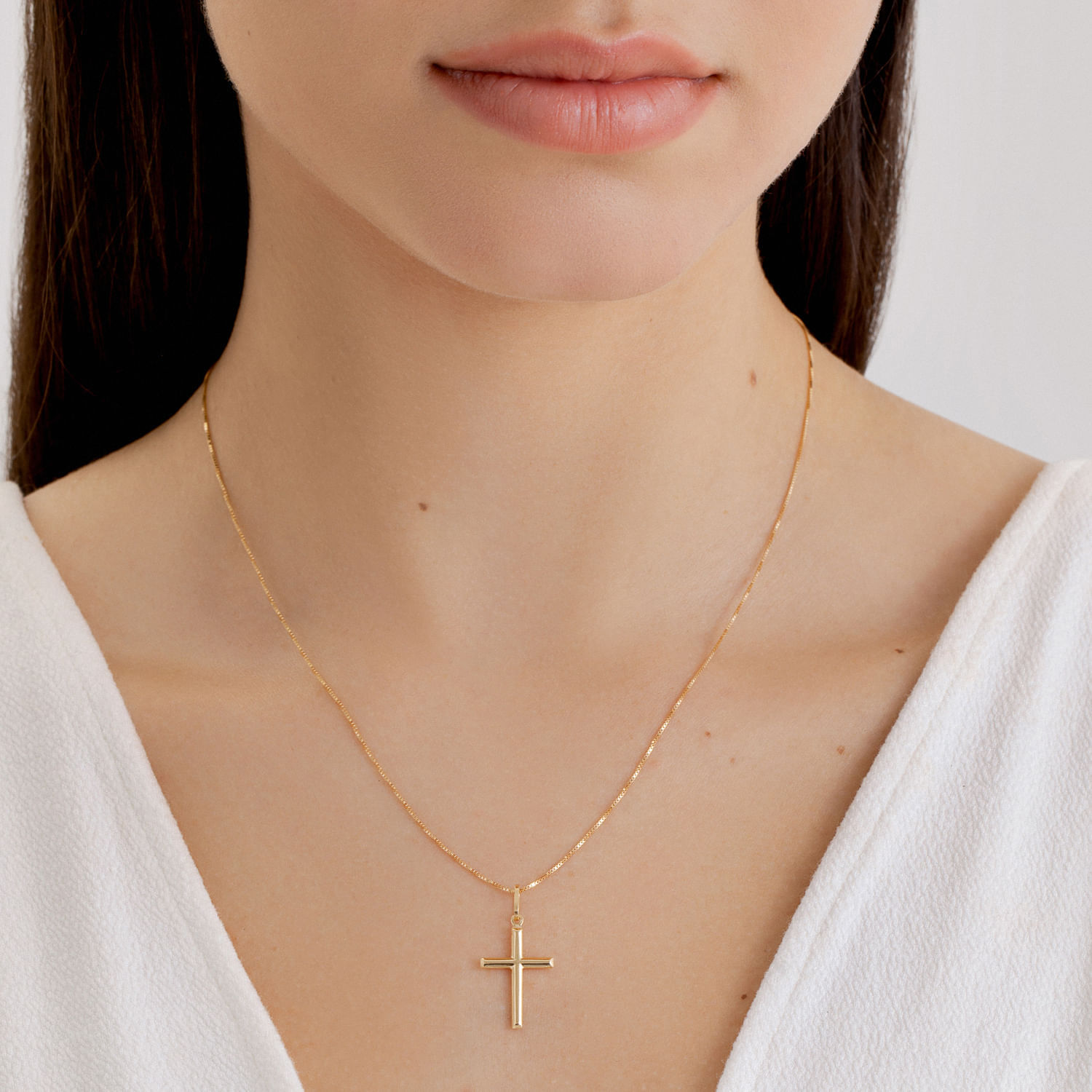 Colar de corrente fina dourada com pingente de cruz.
