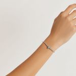 Pulseira de corrente fina com pingente em formato de cruz com pequenos detalhes azuis.