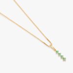 Colar com pingente de ouro com cinco pedras verdes em destaque, em um fundo branco.