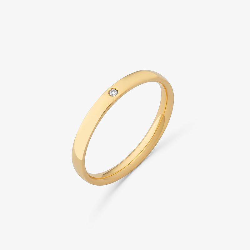 Anel de ouro com uma pedra pequena e transparente, possivelmente um diamante, em uma superfície branca.
