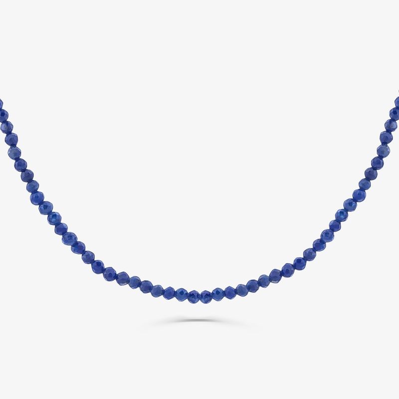 Colar de pedras azuis pequenas, com um efeito de sombra sob a peça, exibido contra fundo branco.