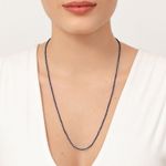 Colar longo de miçangas azuis sendo usado por uma mulher com roupa branca e fundo branco.