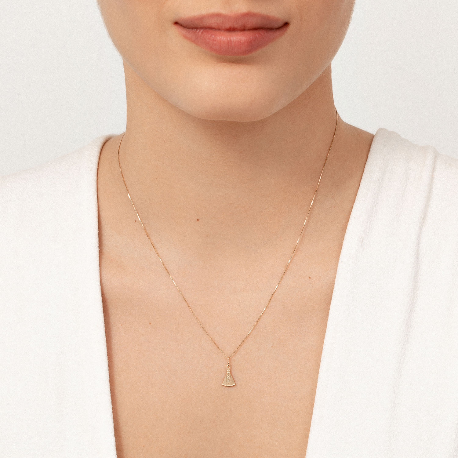 Close-up da foto de uma mulher usando um colar delicado com pingente dourado na nuca.