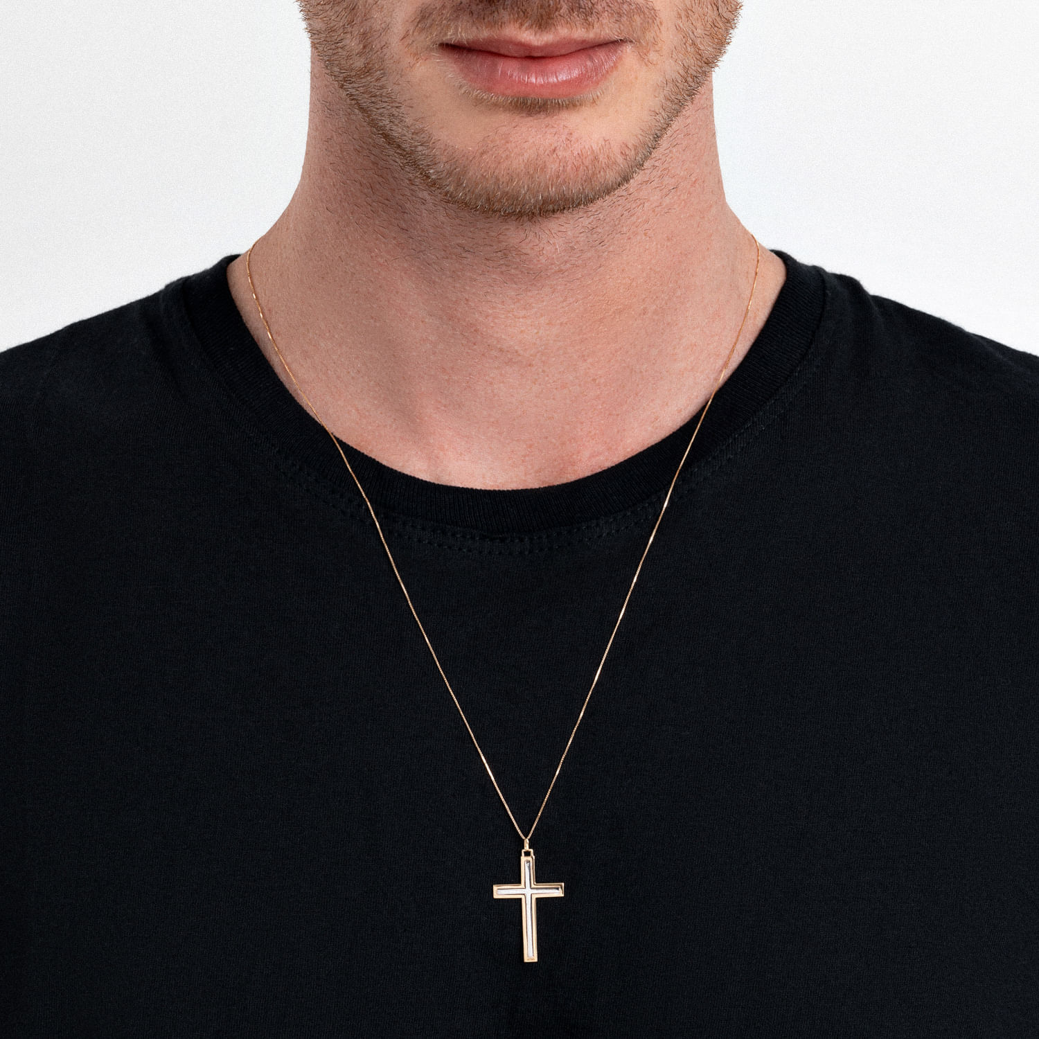 Homem usando uma camiseta preta e um colar dourado com pingente de cruz.