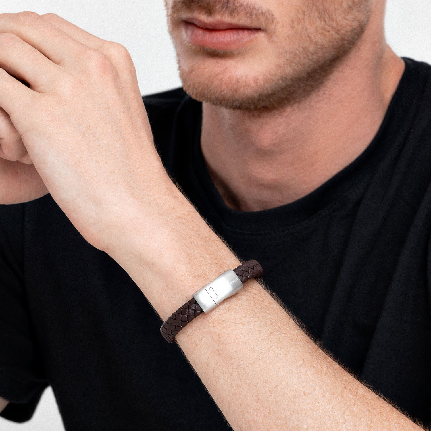 Pulseira de couro marrom com fecho de metal prateado no pulso de um homem.