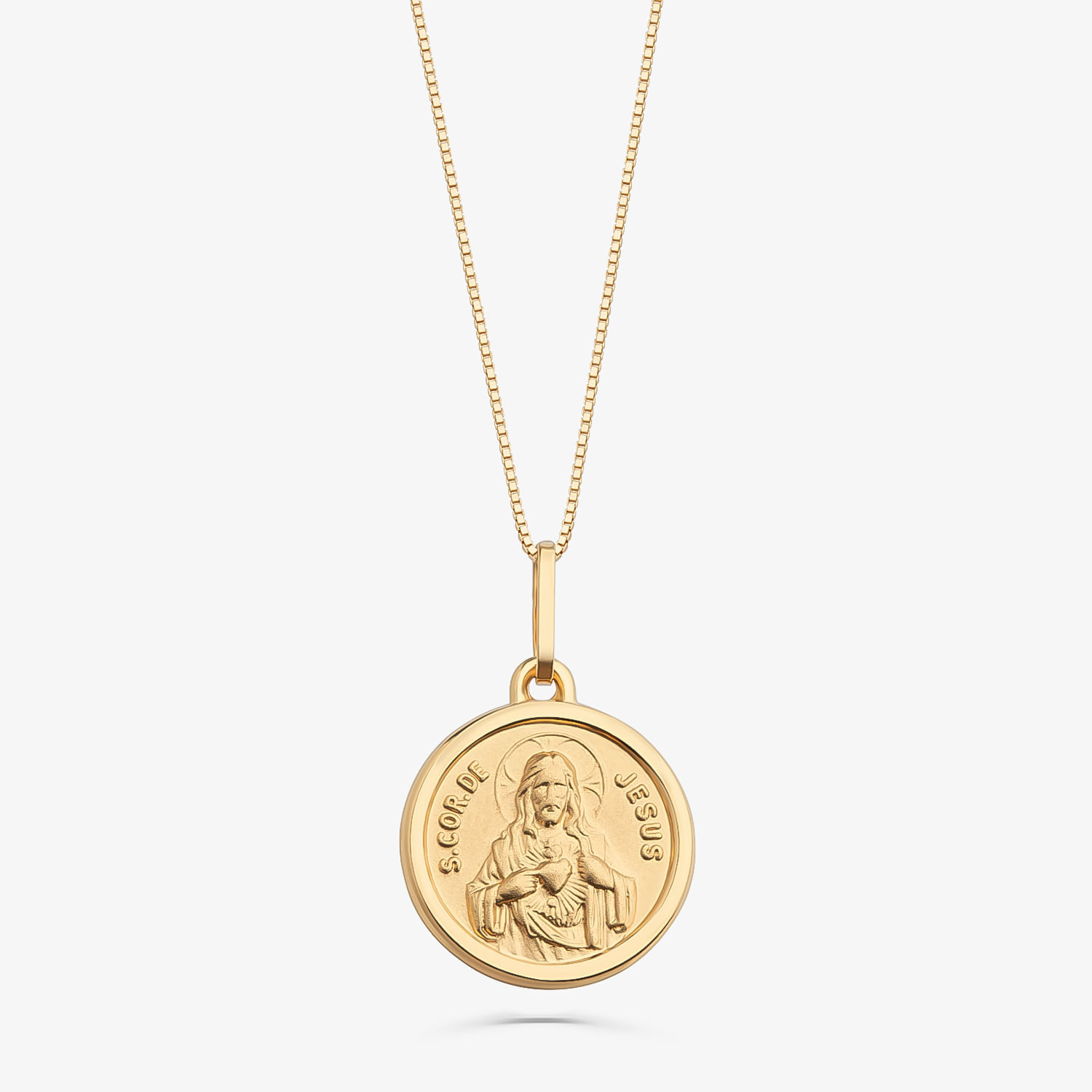 Colar dourado com medalha circular com imagem de Jesus e a inscrição "S. COR DE JESUS".