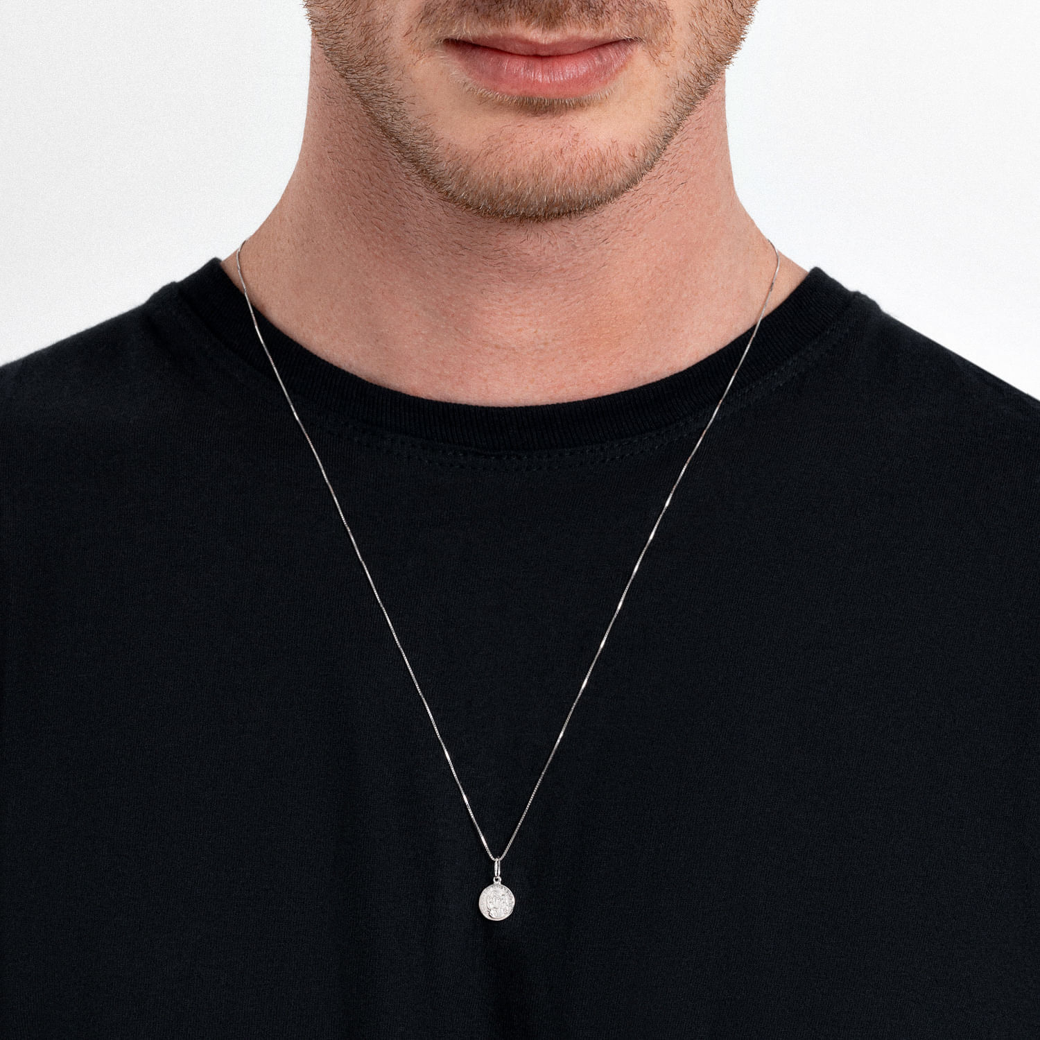 Colar com pingente de diamante em prata, ajustado ao redor do pescoço de um homem com camiseta preta.