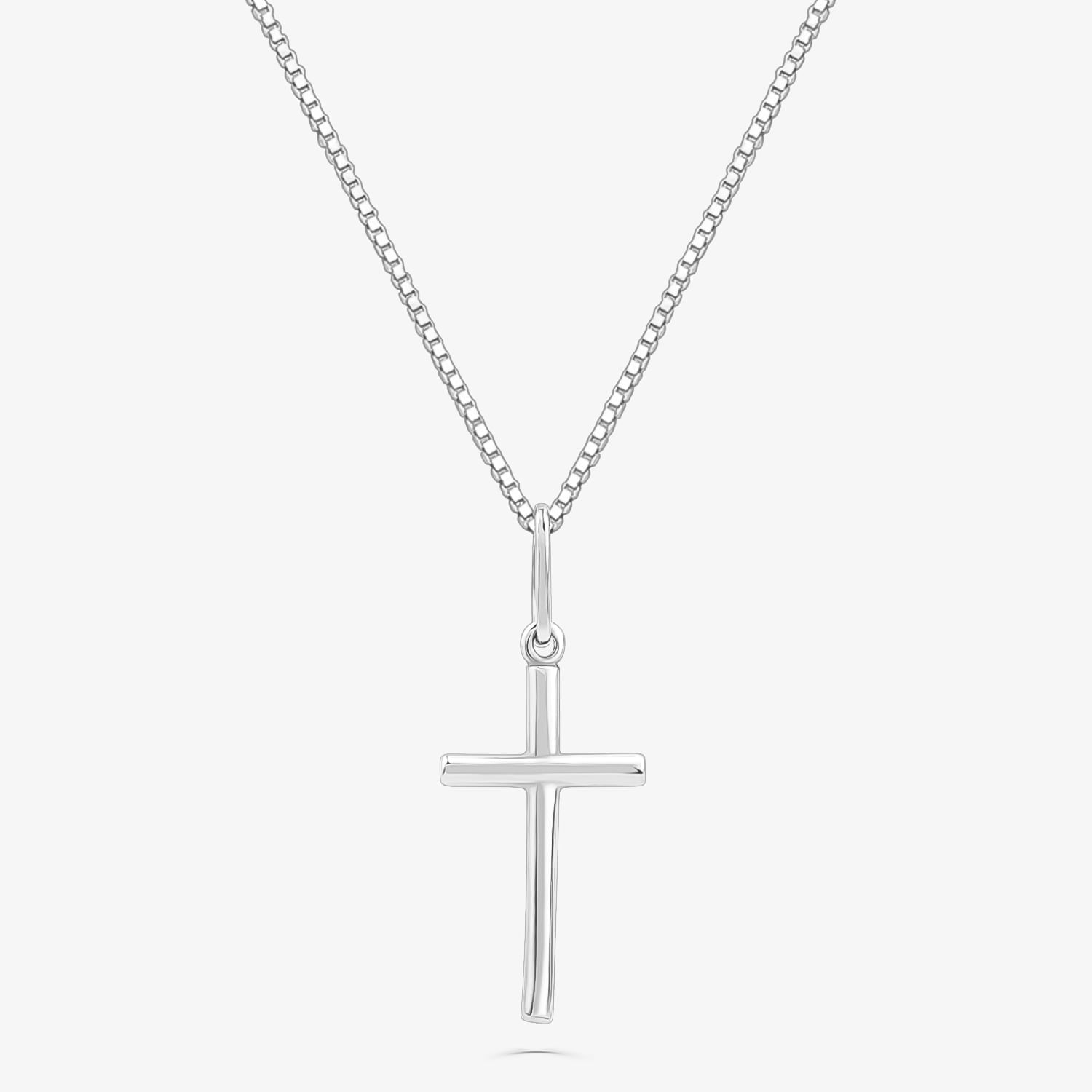 Colar de corrente com pingente de cruz prateada sobre fundo branco.