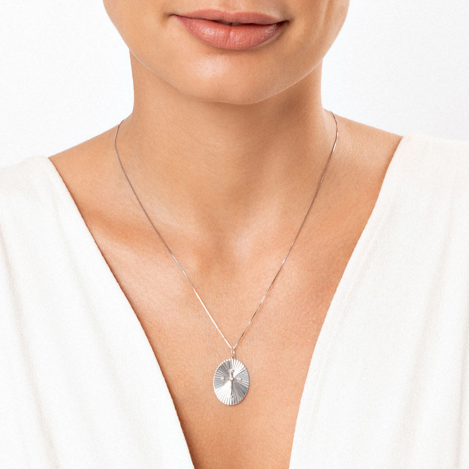 Colar de prata com pingente circular texturizado, usado por uma mulher com blusa branca.