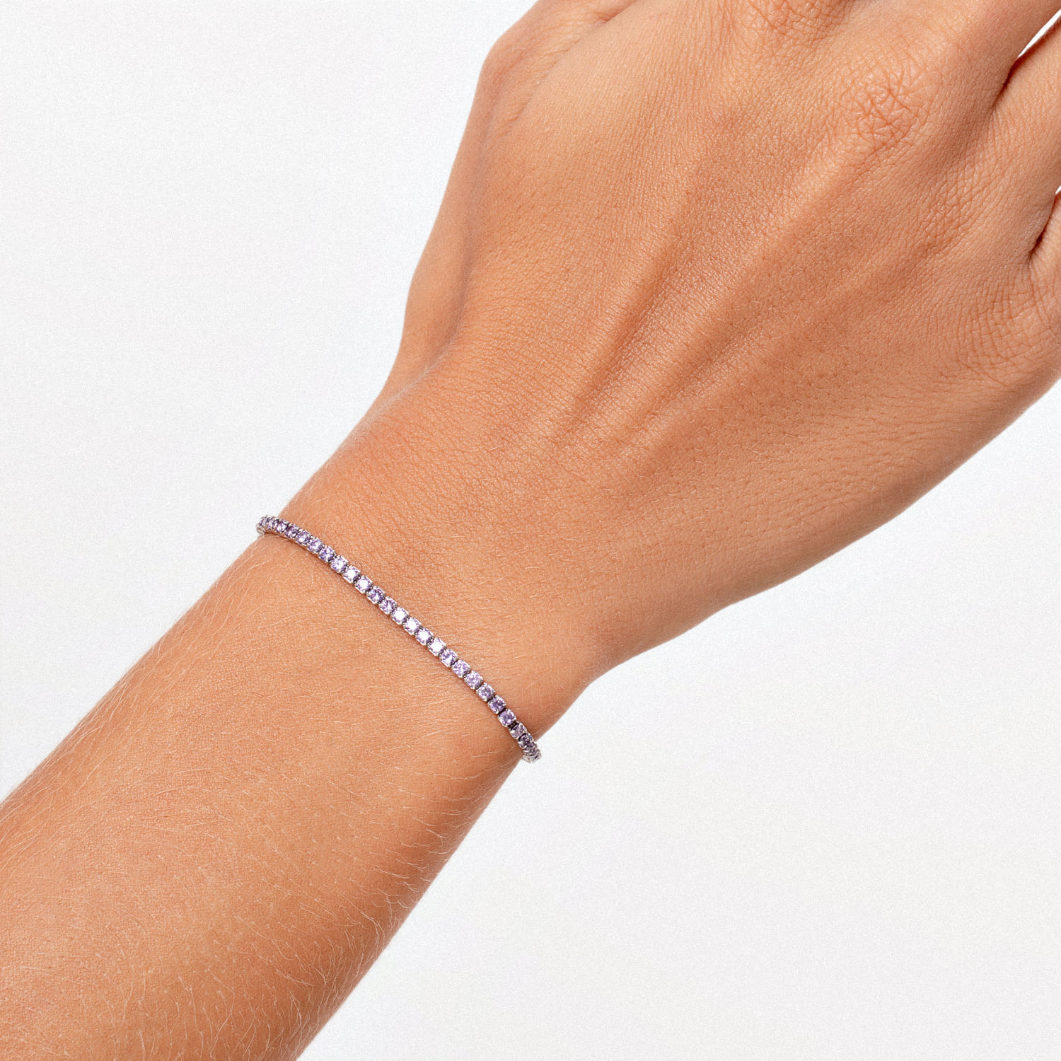 Pulseira com pedras de gemstone lilás na cintura fina do braço de uma pessoa.