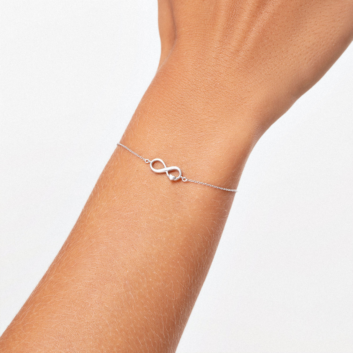 Pulseira de prata com símbolo de infinito na frente do braço.