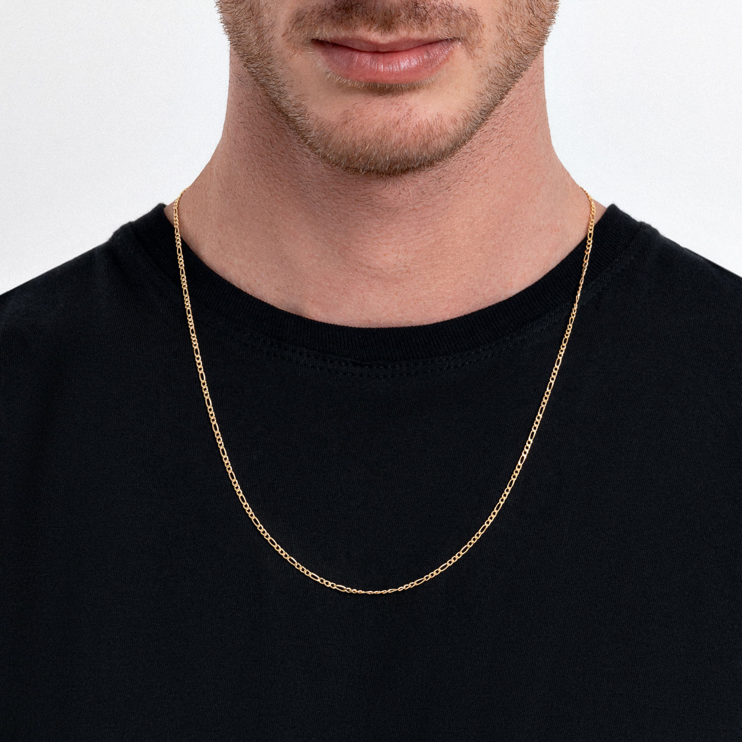 Homem usando uma corrente dourada fina ao redor do pescoço, com camiseta preta.