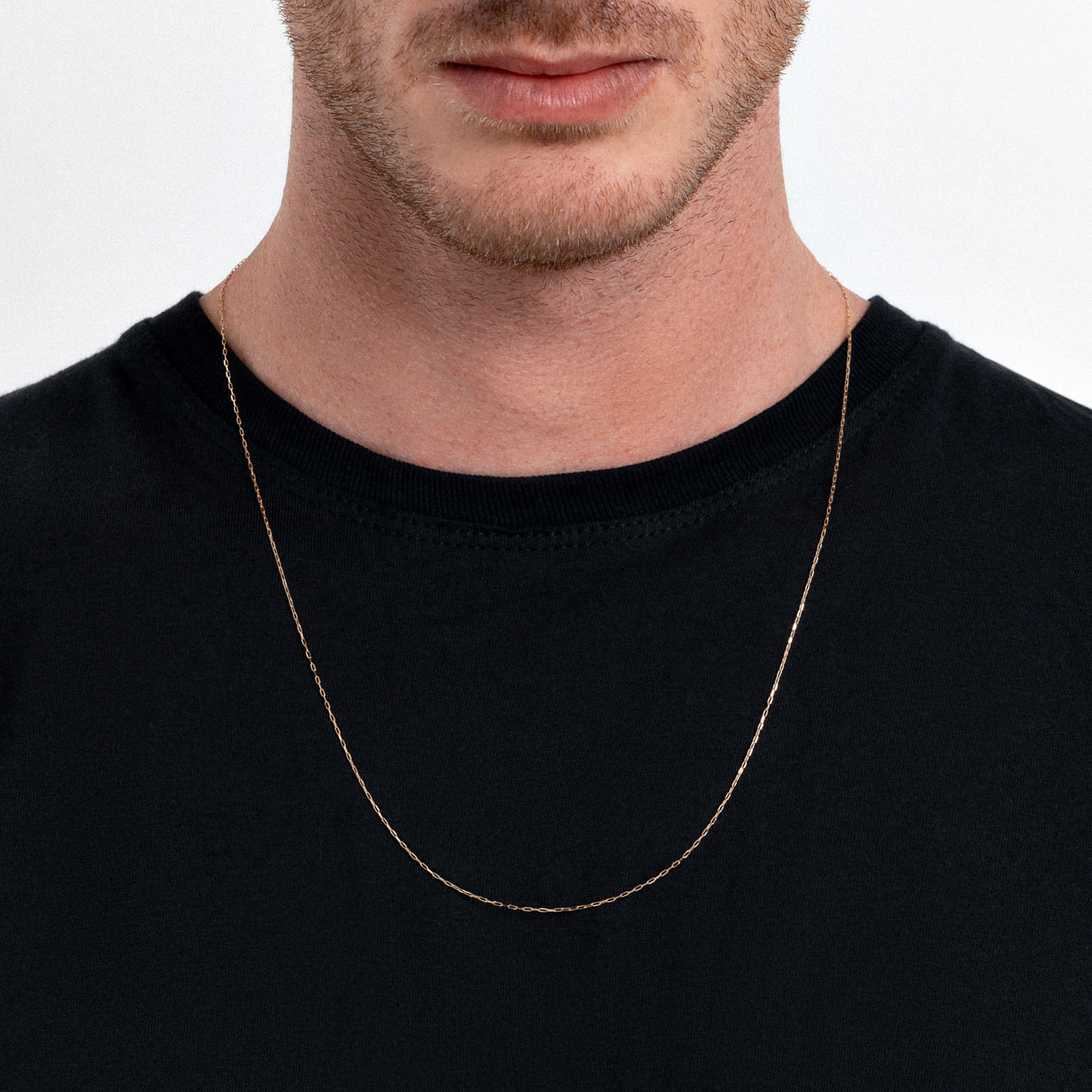 Homem usando uma camiseta preta e uma corrente fina dourada ao redor do pescoço.