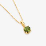 Colar com pingente de ponto de luz com pedra verde em gota, em ouro, sobre fundo branco.
