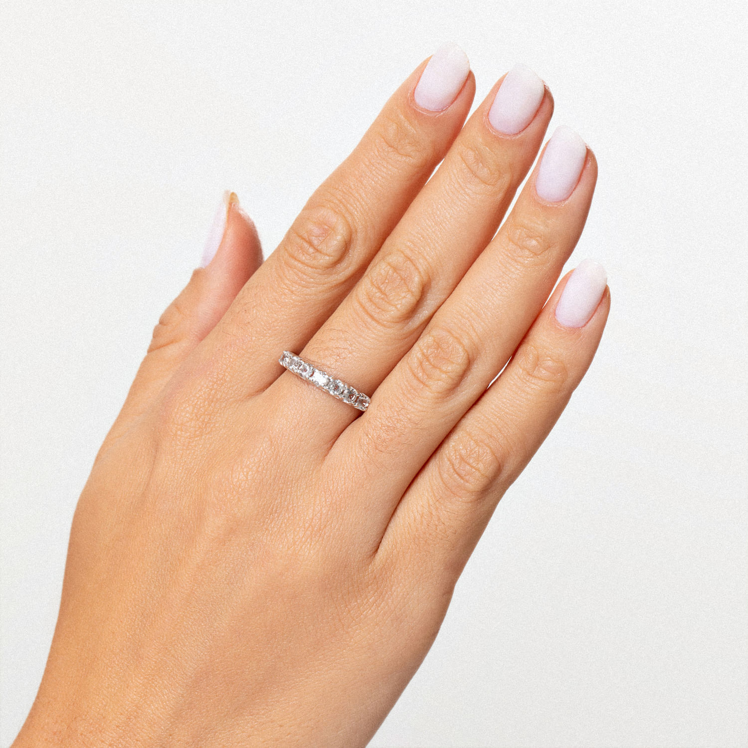 Mão com dedo pintado de branco, usando um anel de diamante no segundo dedo.