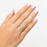 Mão com unhas brancas e anéis de prata com pedras, exibindo um anel de noivado e uma aliança.